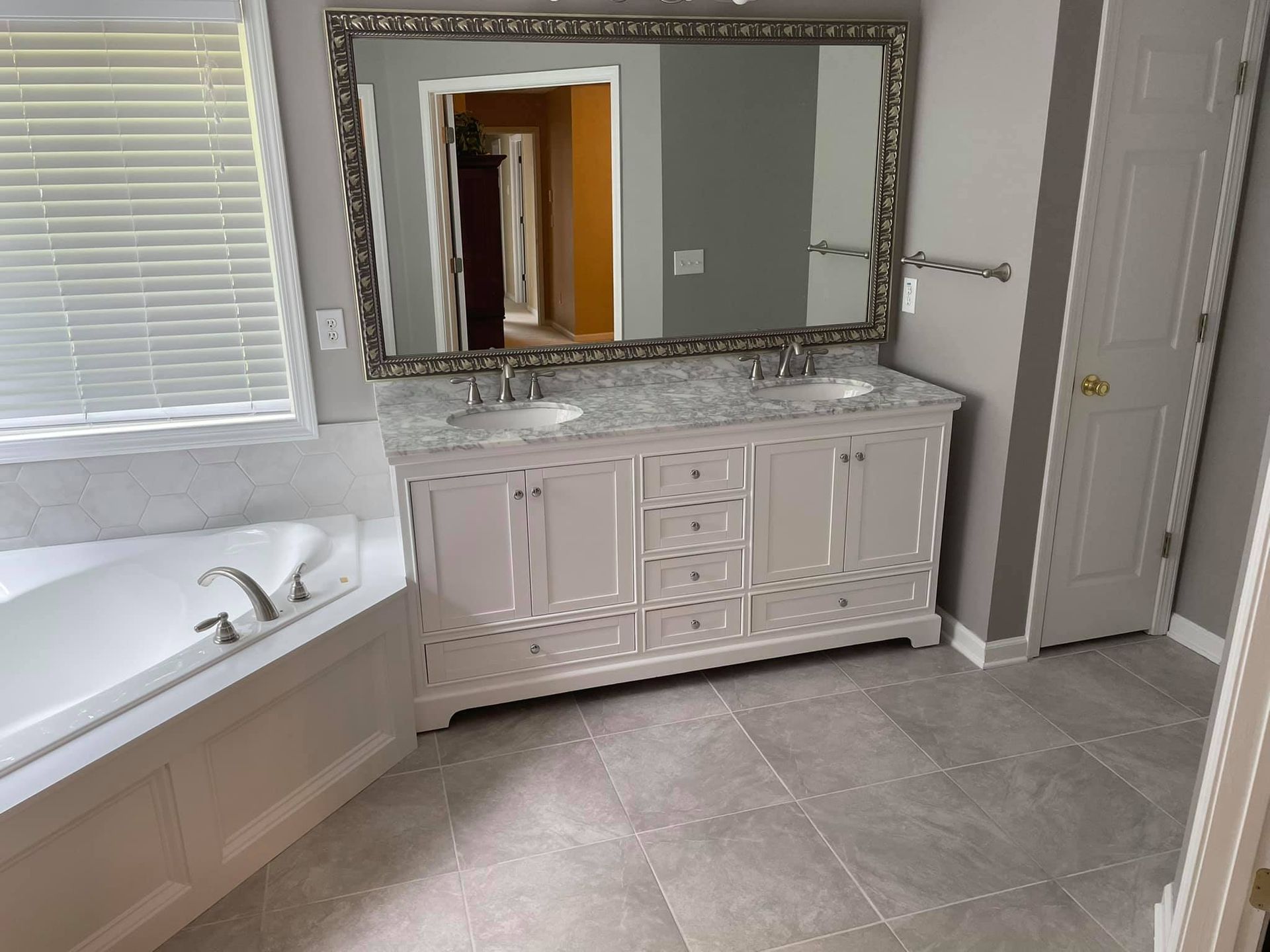 A bathroom with two sinks , a tub and a large mirror.