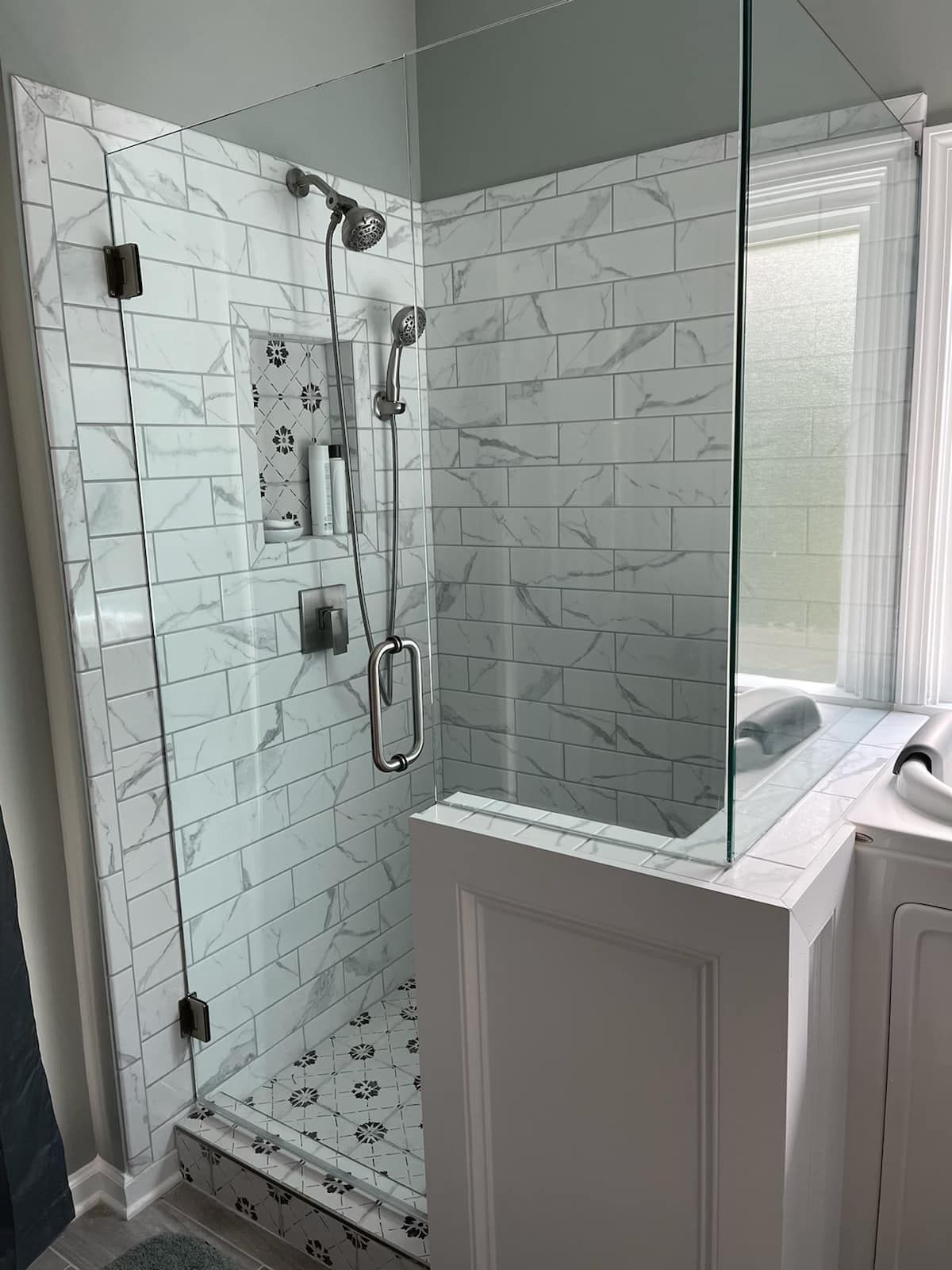 A bathroom with a walk in shower with a glass door.