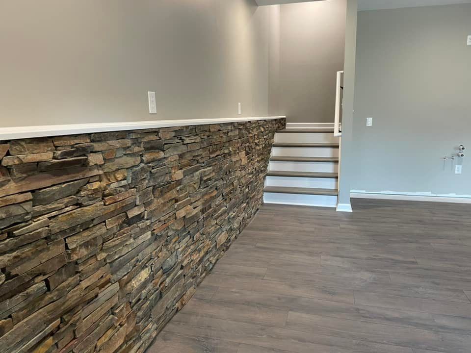 A room with a stone wall and stairs in it.