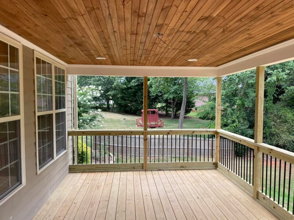 A screened in porch with a wooden ceiling and railing