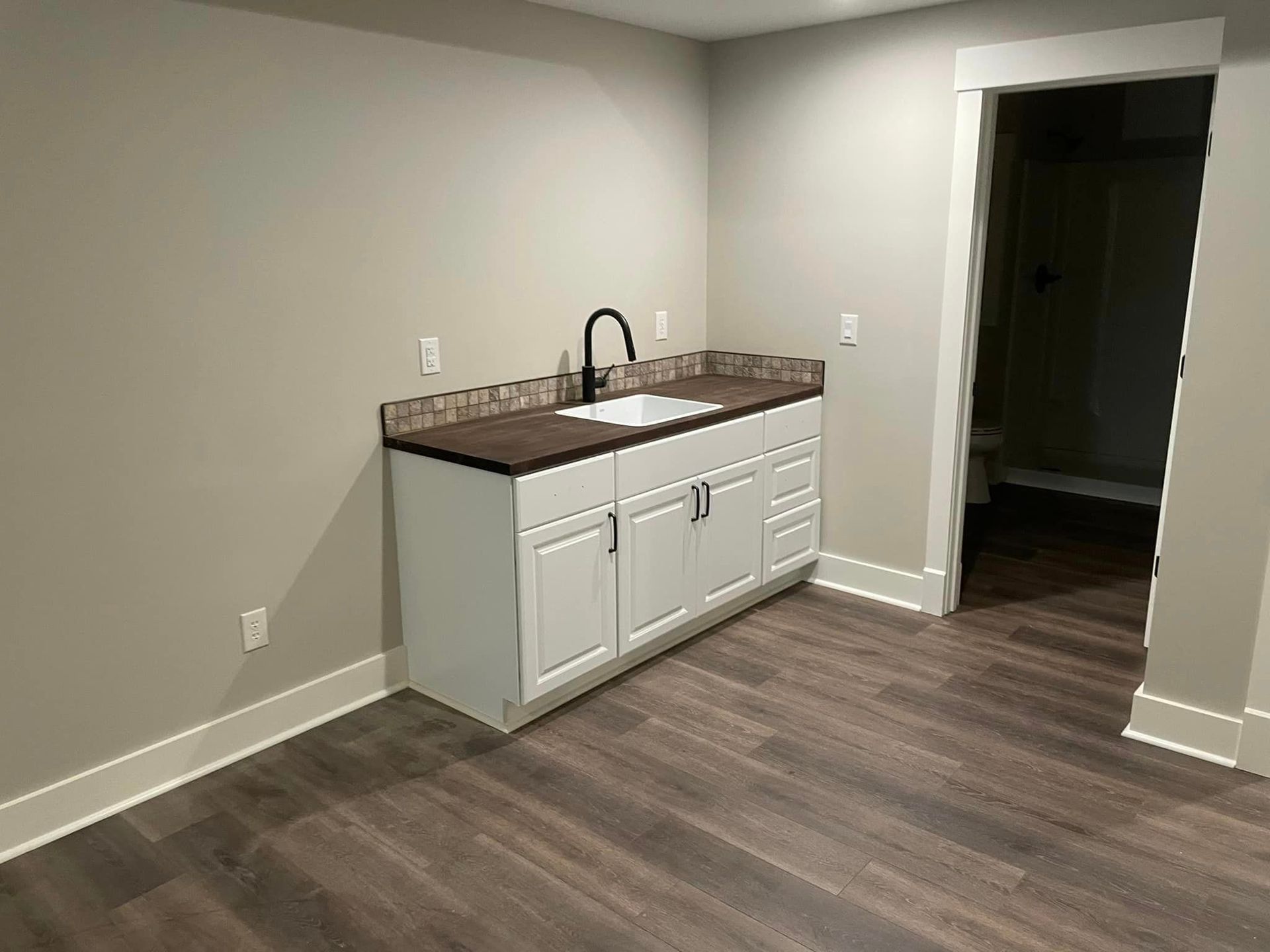 An empty room with a sink and cabinets in it.