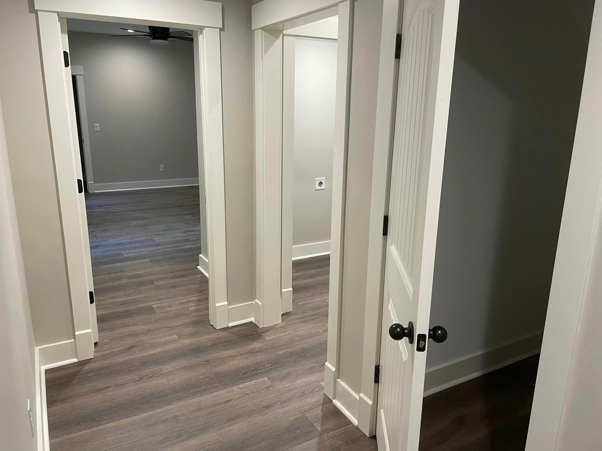 A hallway in a house with wooden floors and white walls.
