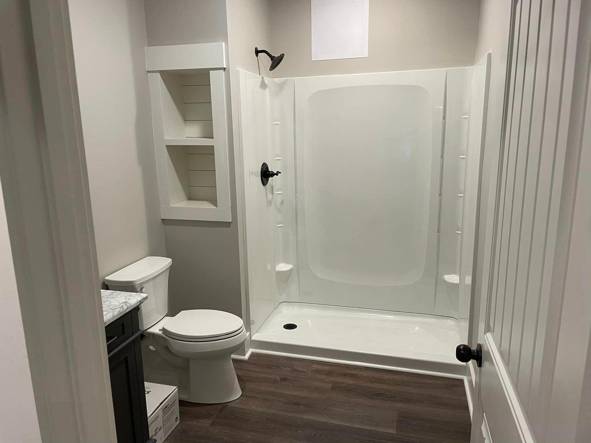 A bathroom with a toilet , shower and sink.