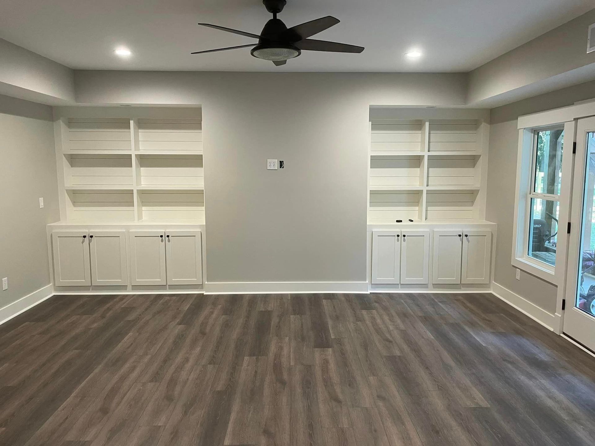 An empty living room with hardwood floors and a ceiling fan.