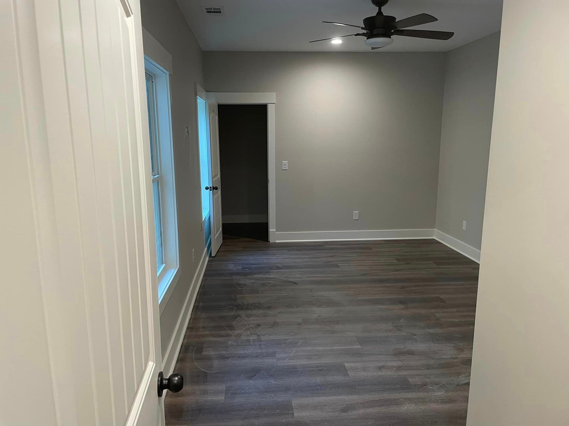 An empty room with hardwood floors and a ceiling fan.