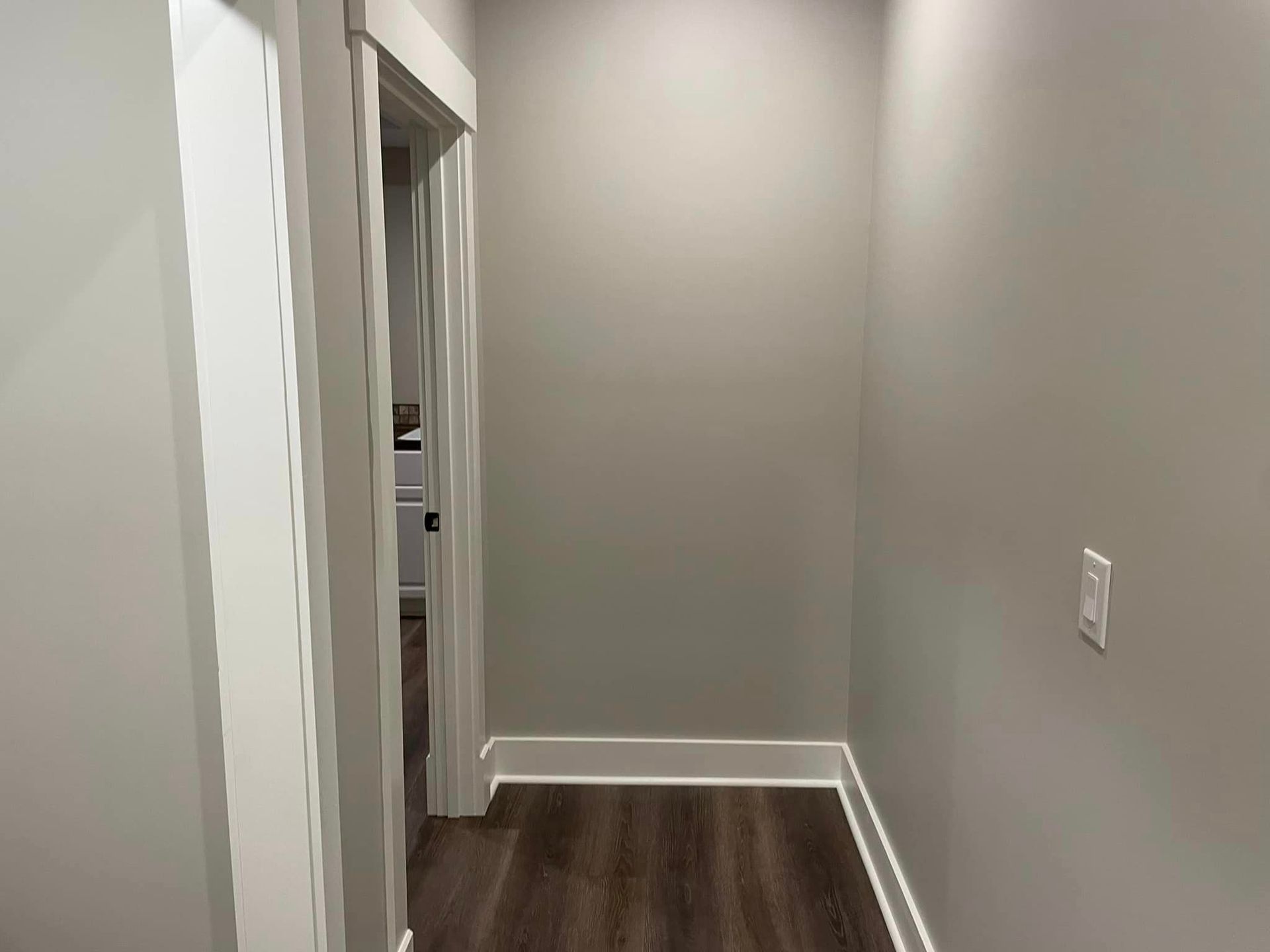 A hallway with a wooden floor and white walls in a house.