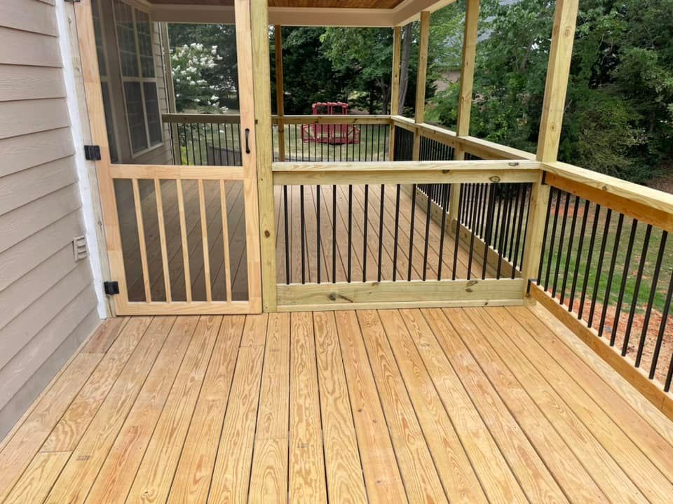 A screened in porch with a wooden deck and railing