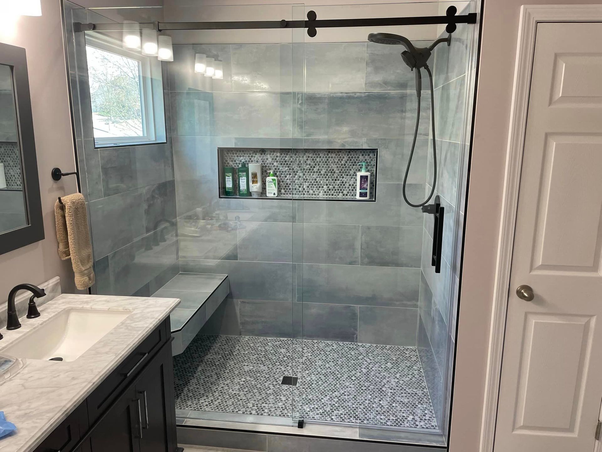 A bathroom with a walk in shower and a sink.