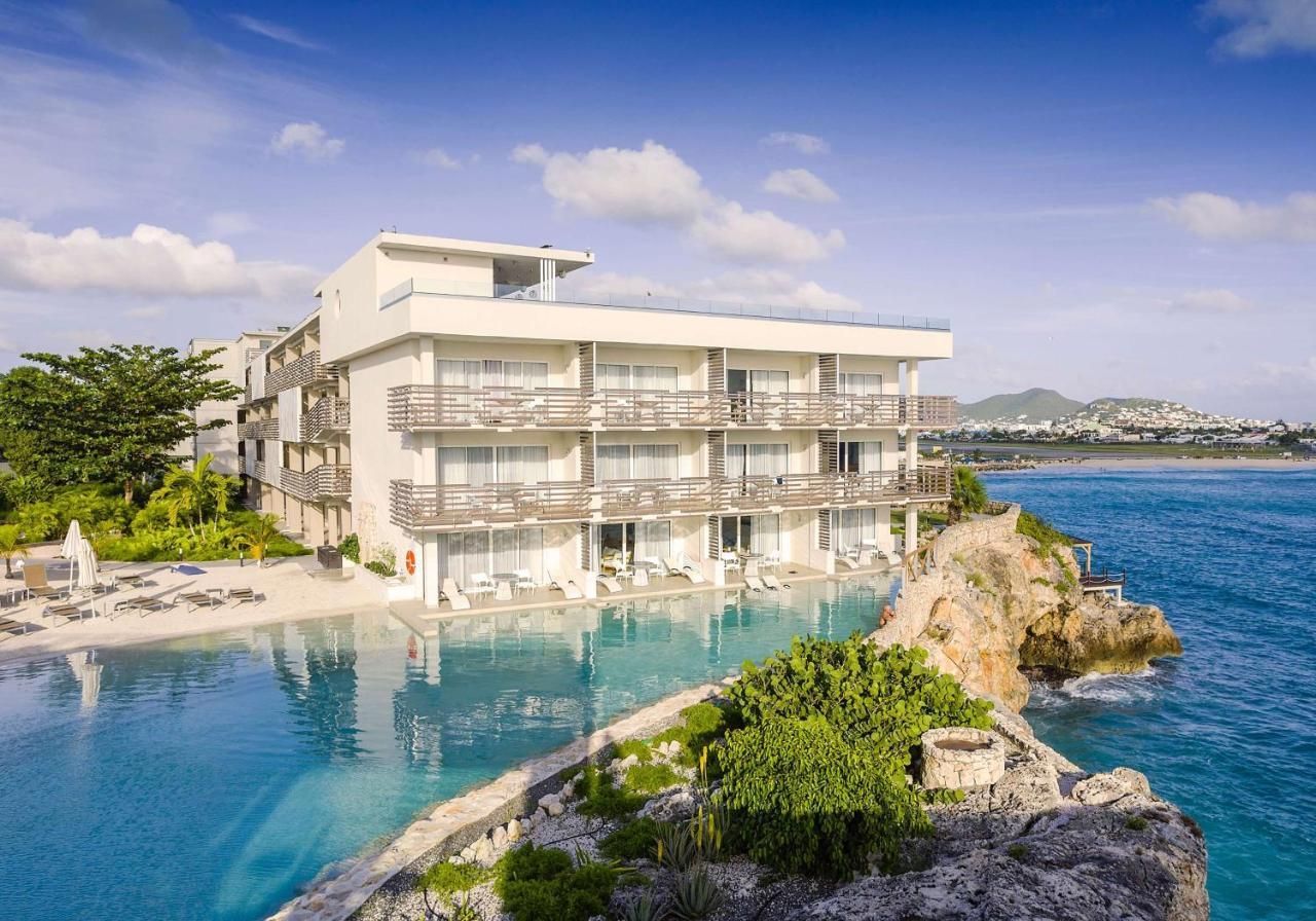 A large white building is sitting on top of a cliff overlooking the ocean.