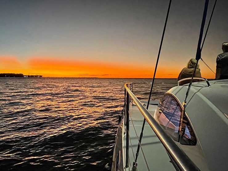 Two people are sitting on a boat in the ocean at sunset.