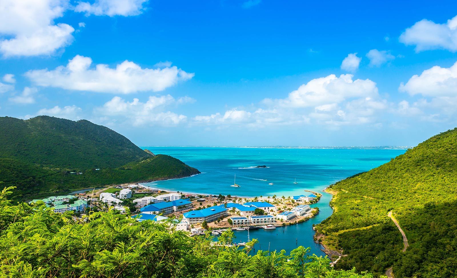 An aerial view of a small island in the middle of the ocean surrounded by mountains.