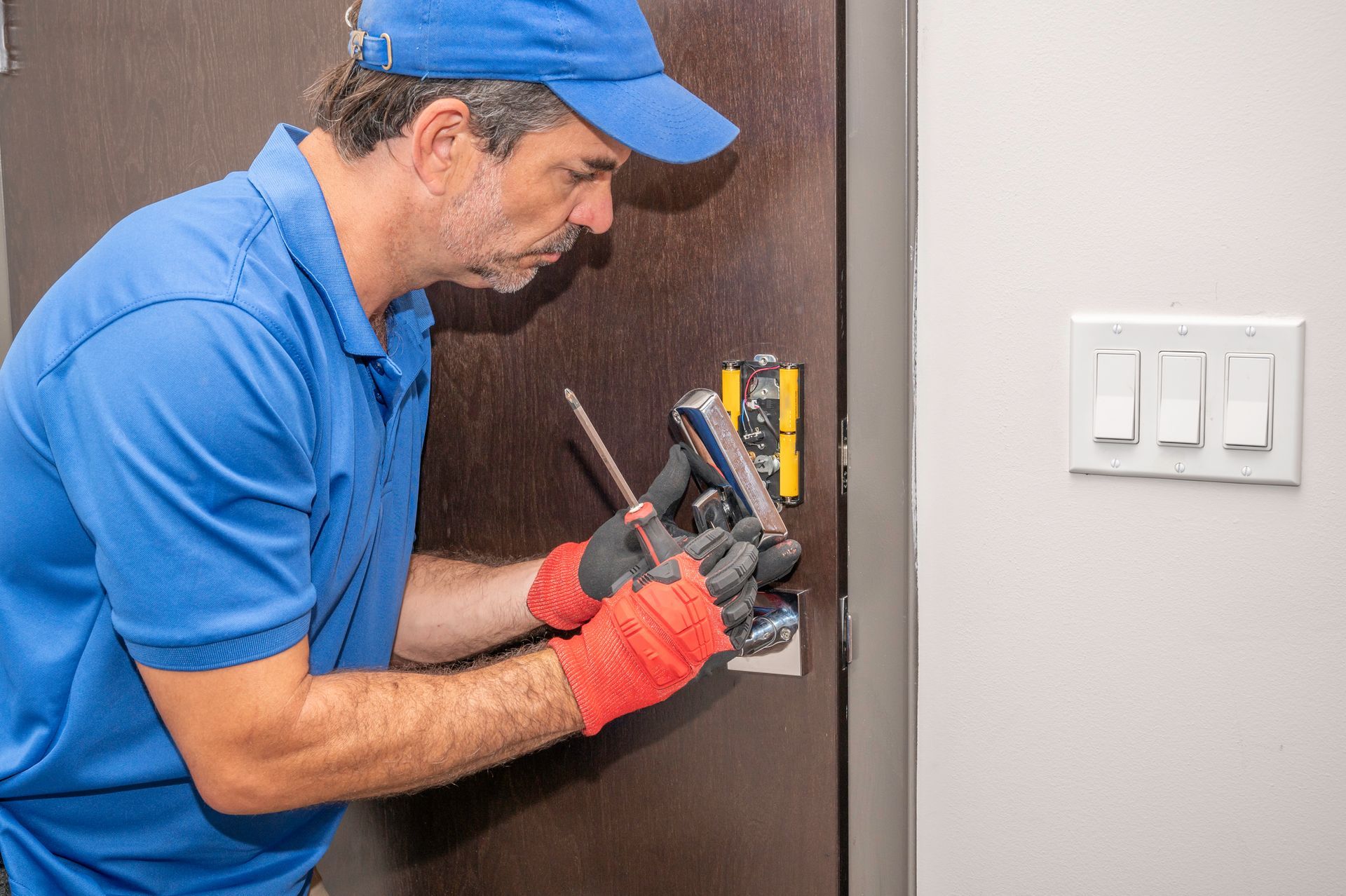 A man is fixing a door lock with a screwdriver.