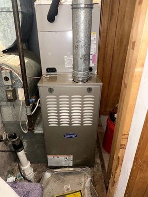 Gas furnace in a cramped utility closet with metal venting and ductwork.