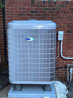 Outdoor air conditioner unit beside a brick wall, with conduit and gravel base