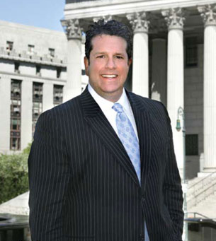 Man in pinstripe suit smiles in front of a courthouse with columns.