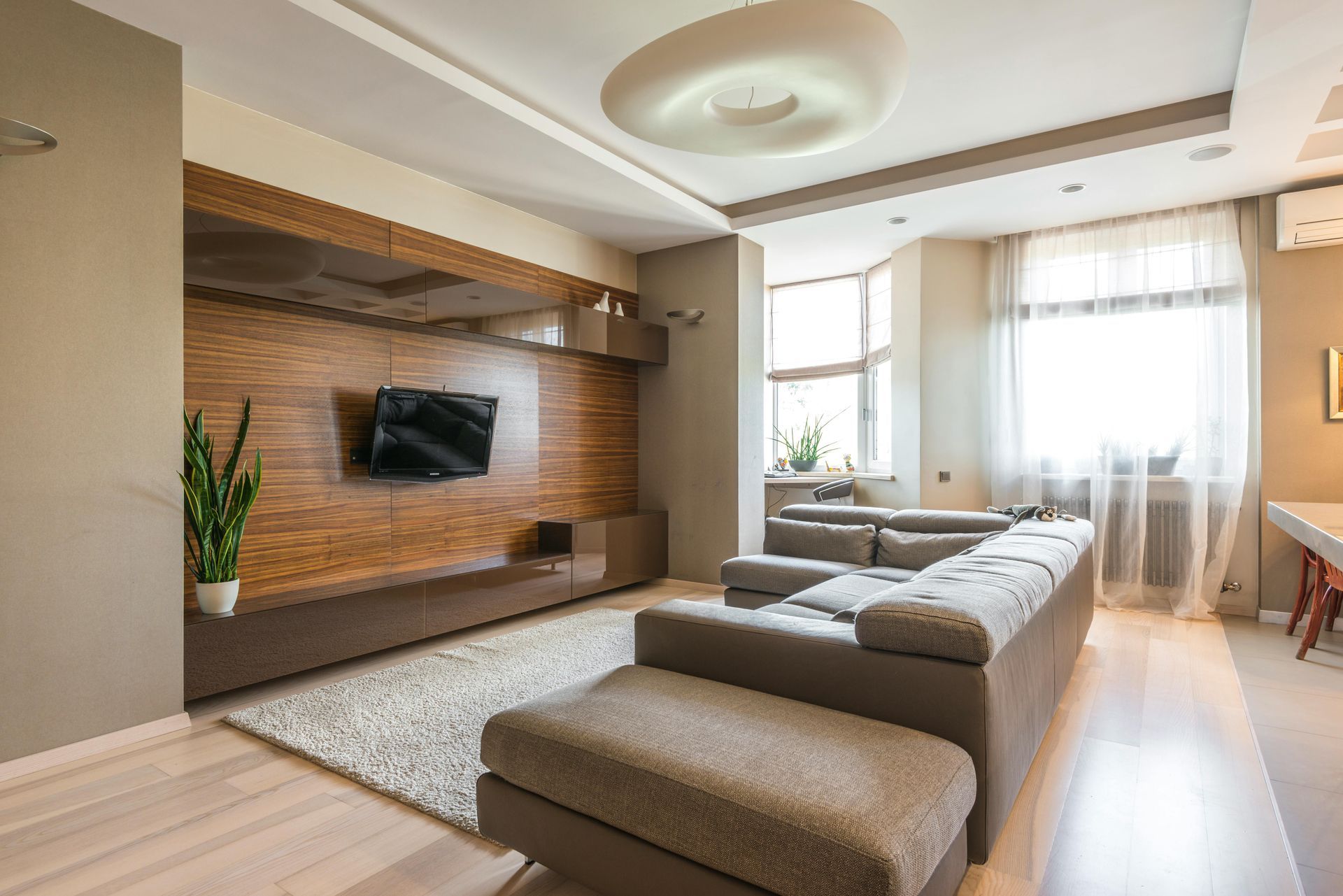 Modern living room with sectional sofa, wood accent wall, and large windows.