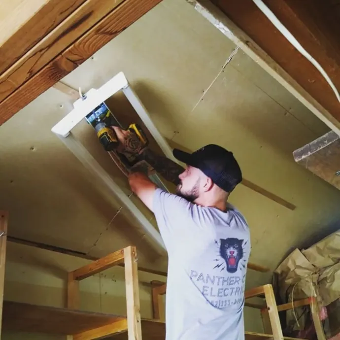 Panther City Electric LLC - A man wearing a panthers electric shirt is working on a light fixture