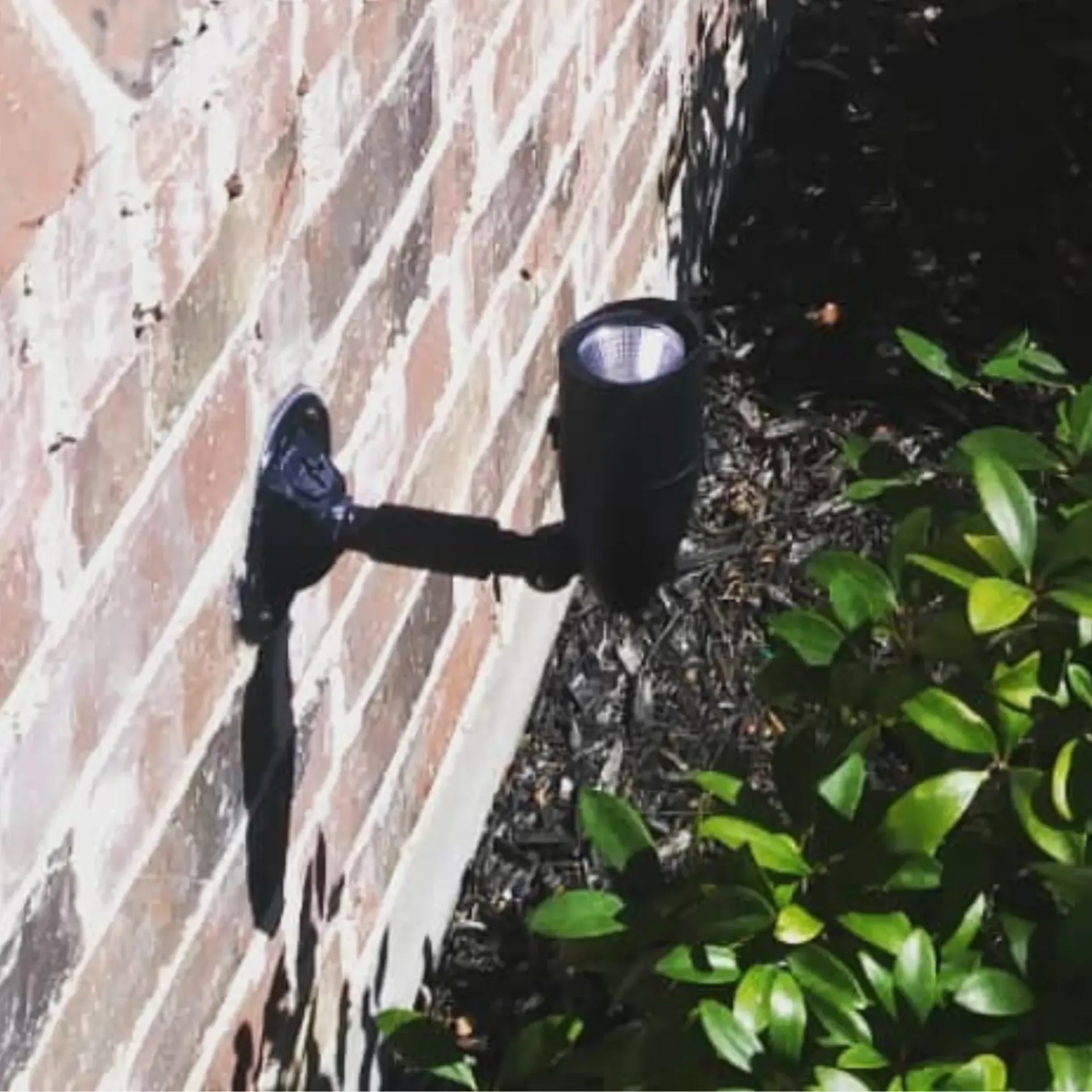Panther City Electric LLC - A black light is mounted on a brick wall next to a bush.