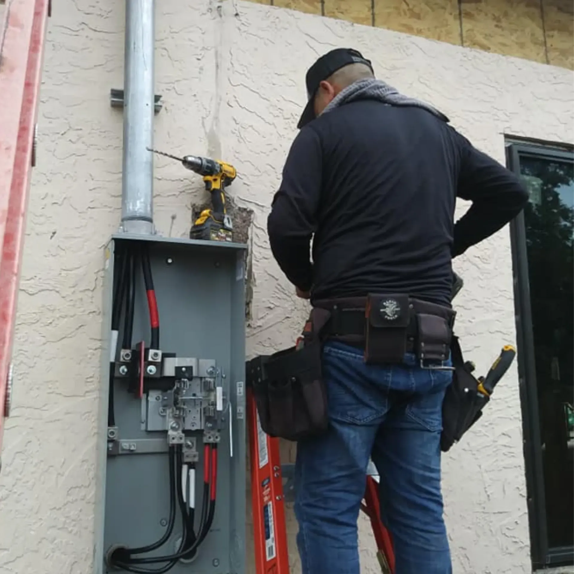 Panther City Electric LLC - A man is standing on a ladder working on an electrical box