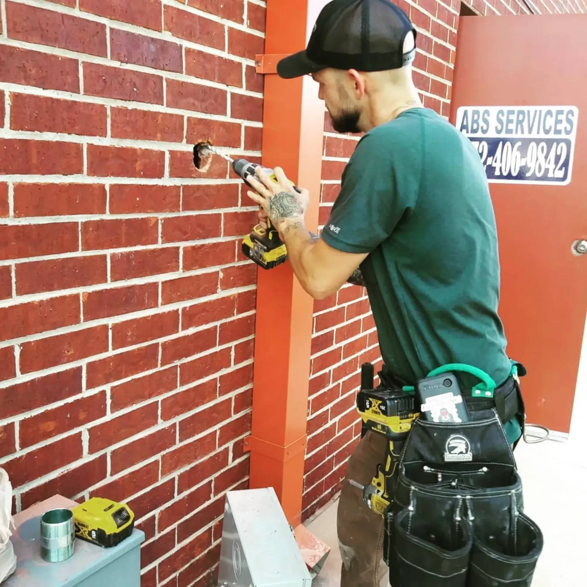 Panther City Electric LLC - A man is working on a brick wall in front of a sign that says abs services