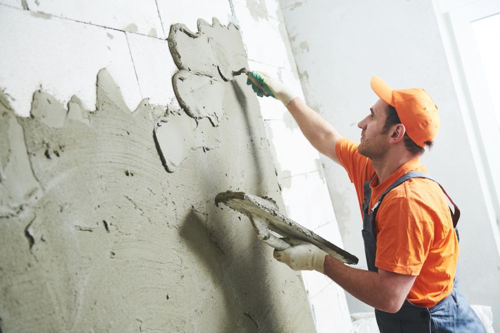 A Man Is Plastering A Wall With A Trowel — Eldred Waterproofing In Trinity Beach, QLD