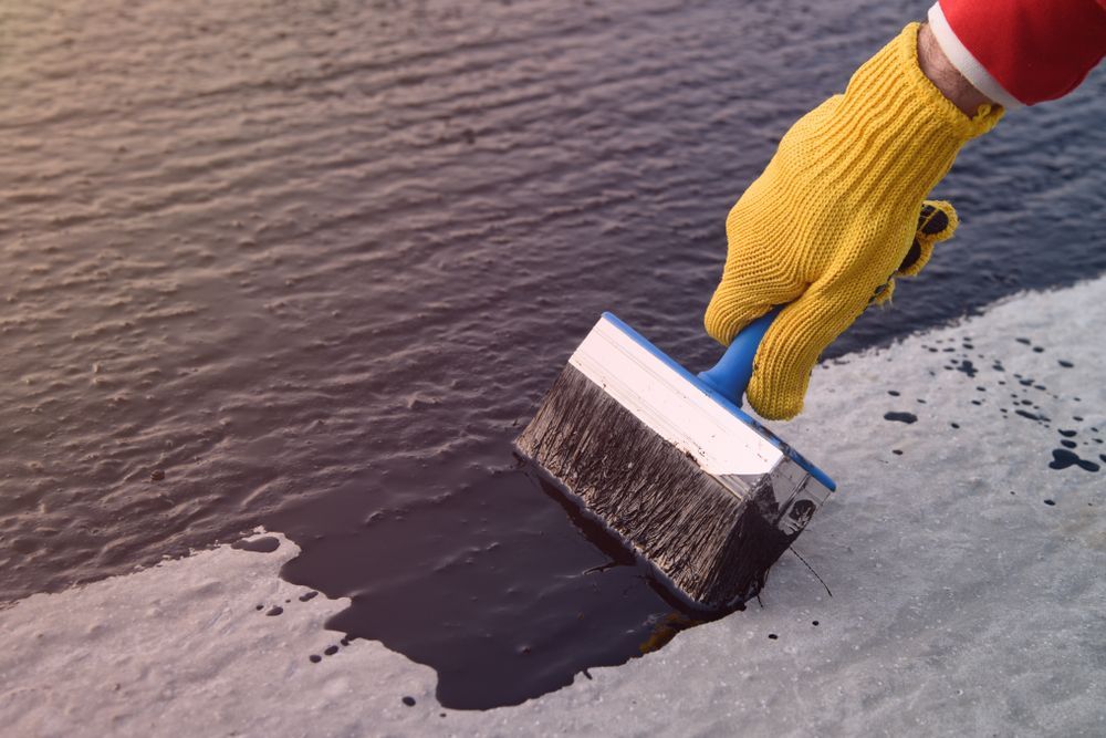 A Person Is Painting A Concrete Surface With A Brush — Eldred Waterproofing In Whitfield, QLD
