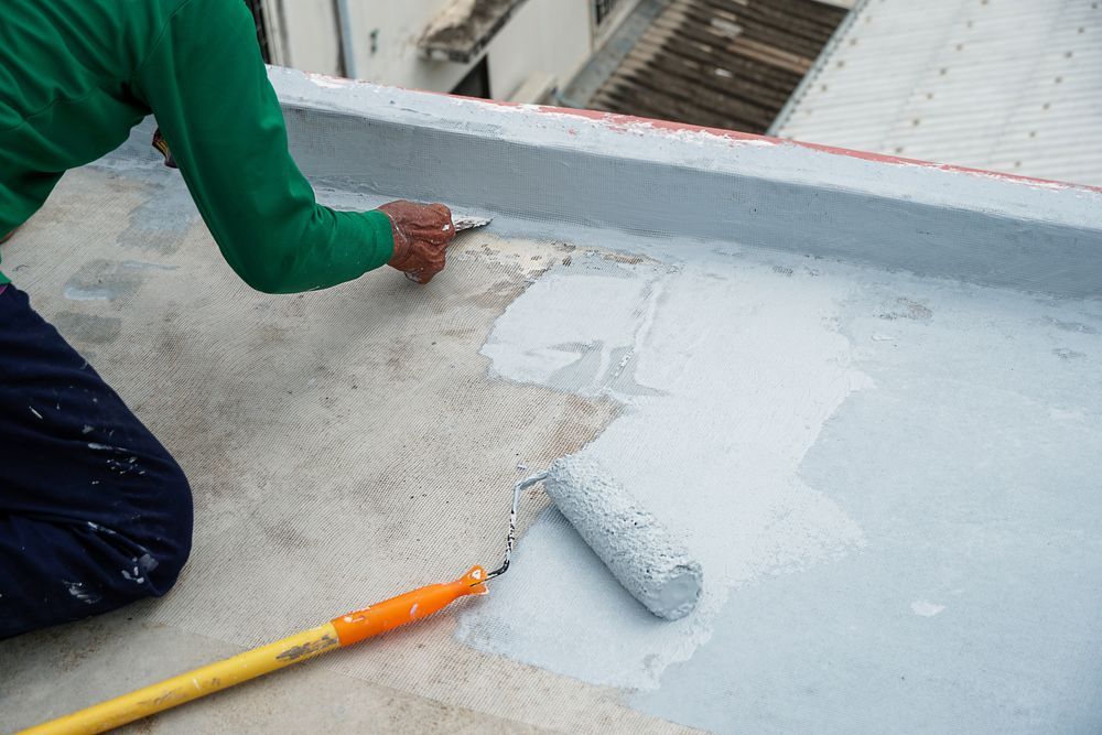 A Man Is Painting A Roof With A Roller — Eldred Waterproofing In Gordonvale, QLD