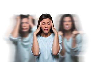 Woman holding her head with blurred duplicates on both sides, suggesting confusion or stress