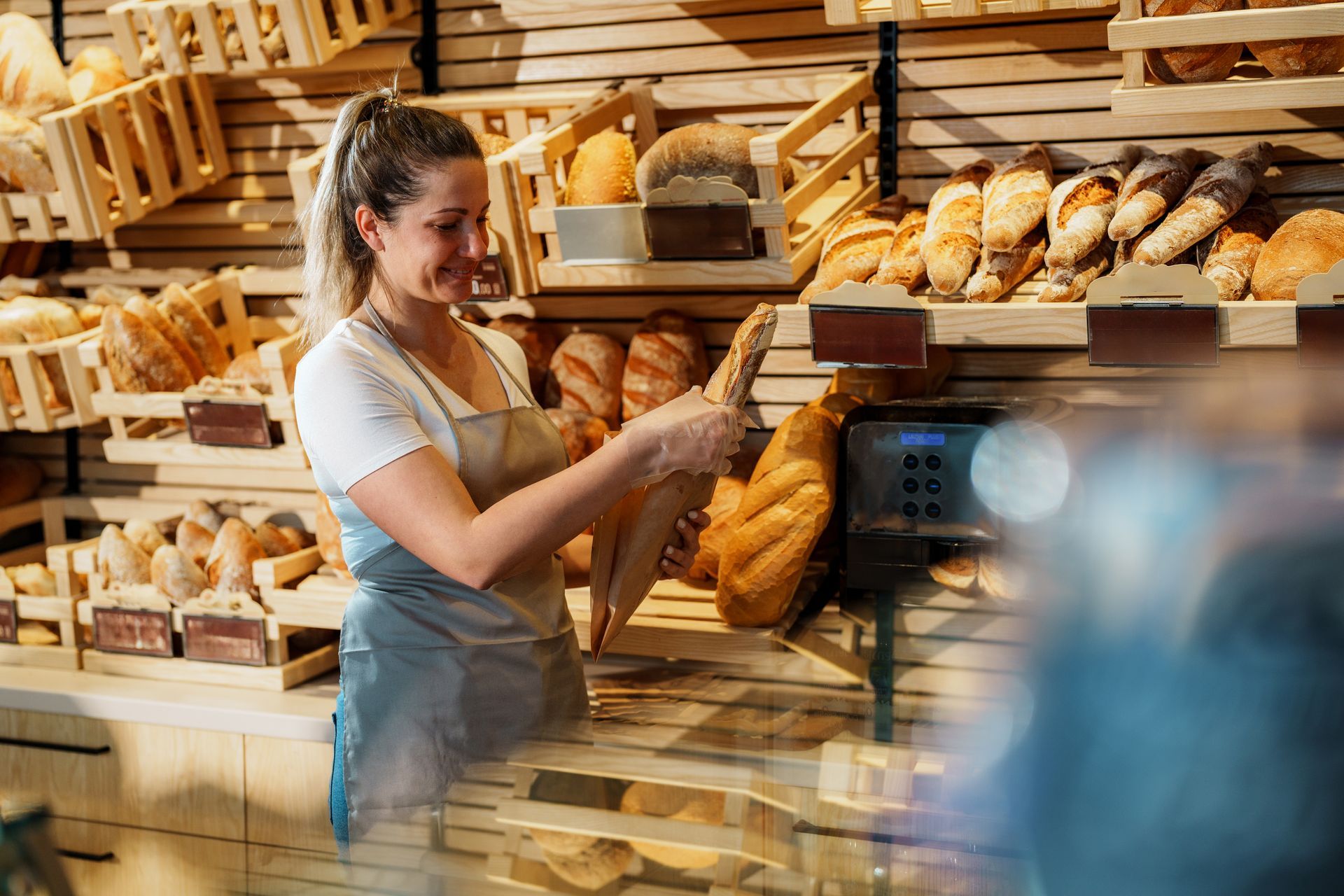 Woman holding bread in a bakery, showcasing quality wholesale bakery products. Woman holding bread in a bakery, showcasing quality wholesale bakery products.