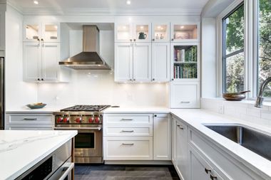 Bright, modern kitchen with white cabinetry, marble countertops, stainless steel appliances, and a window above the sink. Bright, modern kitchen with white cabinetry, marble countertops, stainless steel appliances, and a window above the sink.