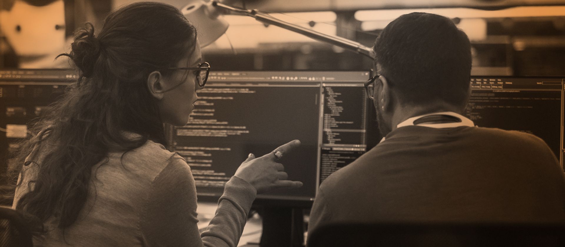 Female and male professionals reviewing data on monitors.