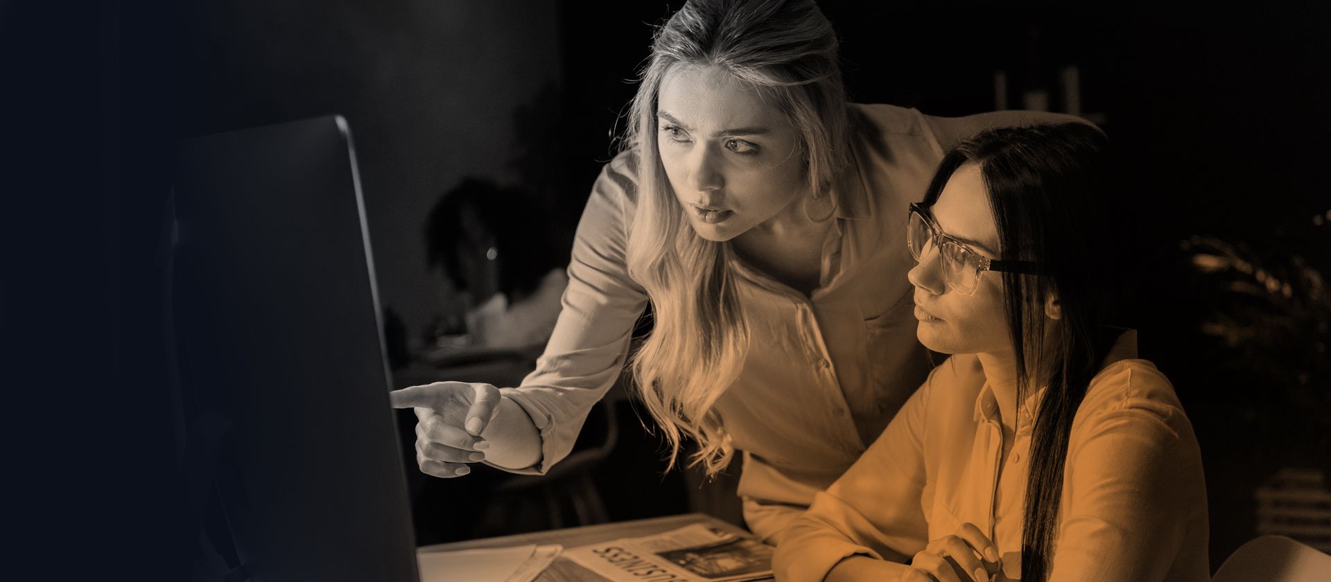Two women are looking at a computer screen together.