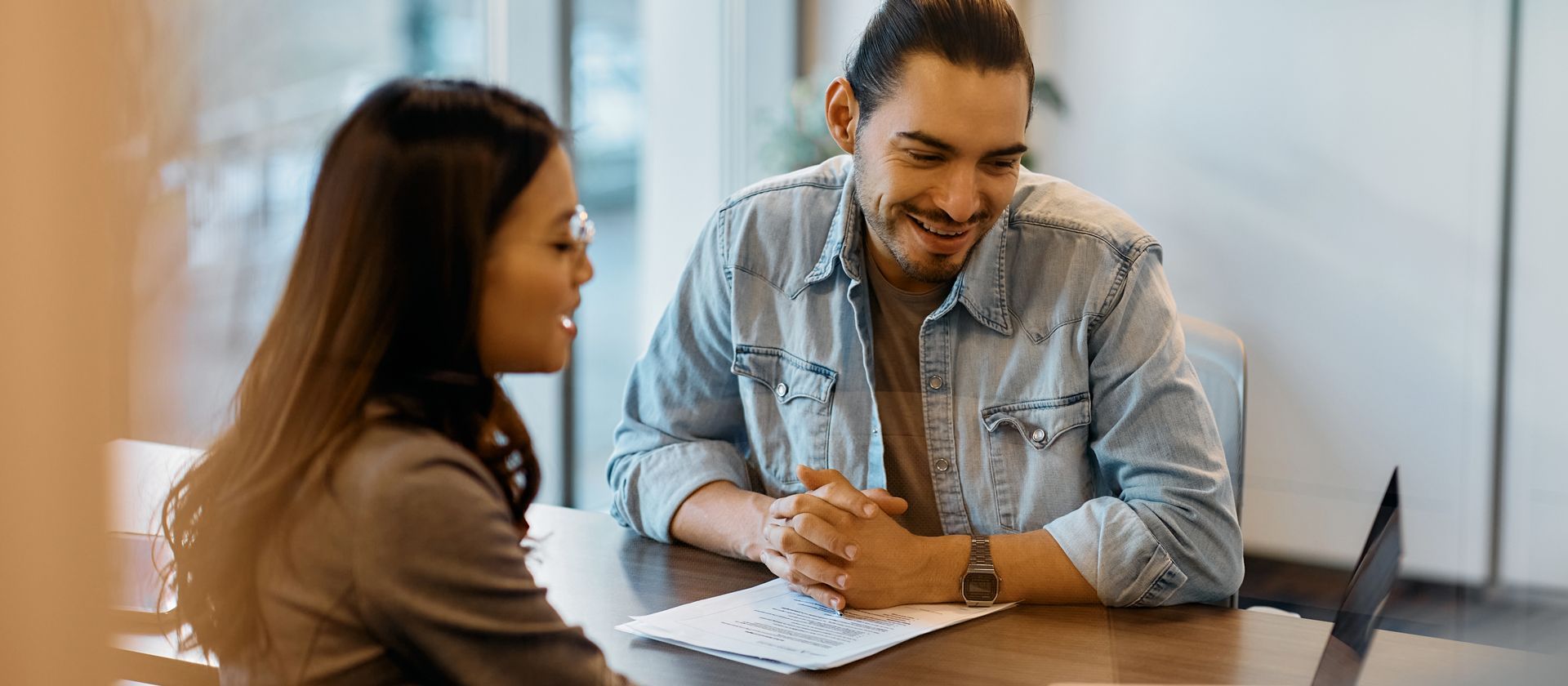 A man and a woman are sitting at a table talking to each other.