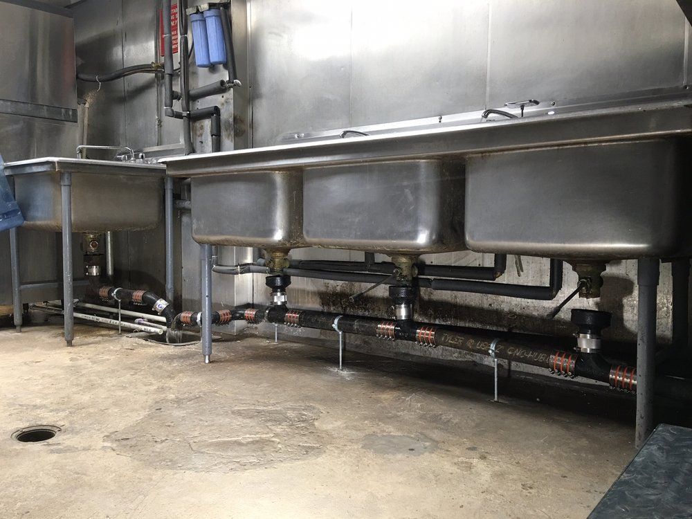 A row of stainless steel sinks in a kitchen.