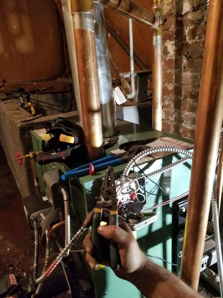 A person is working on a boiler in a basement.