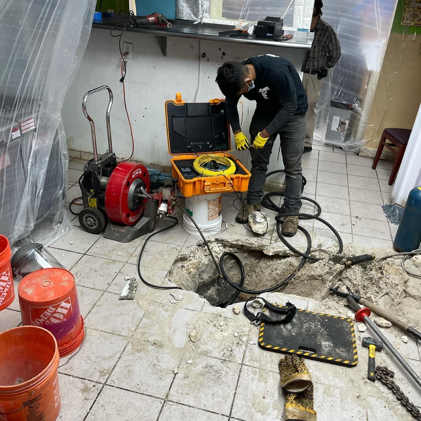 A man is working on a drain in a room.