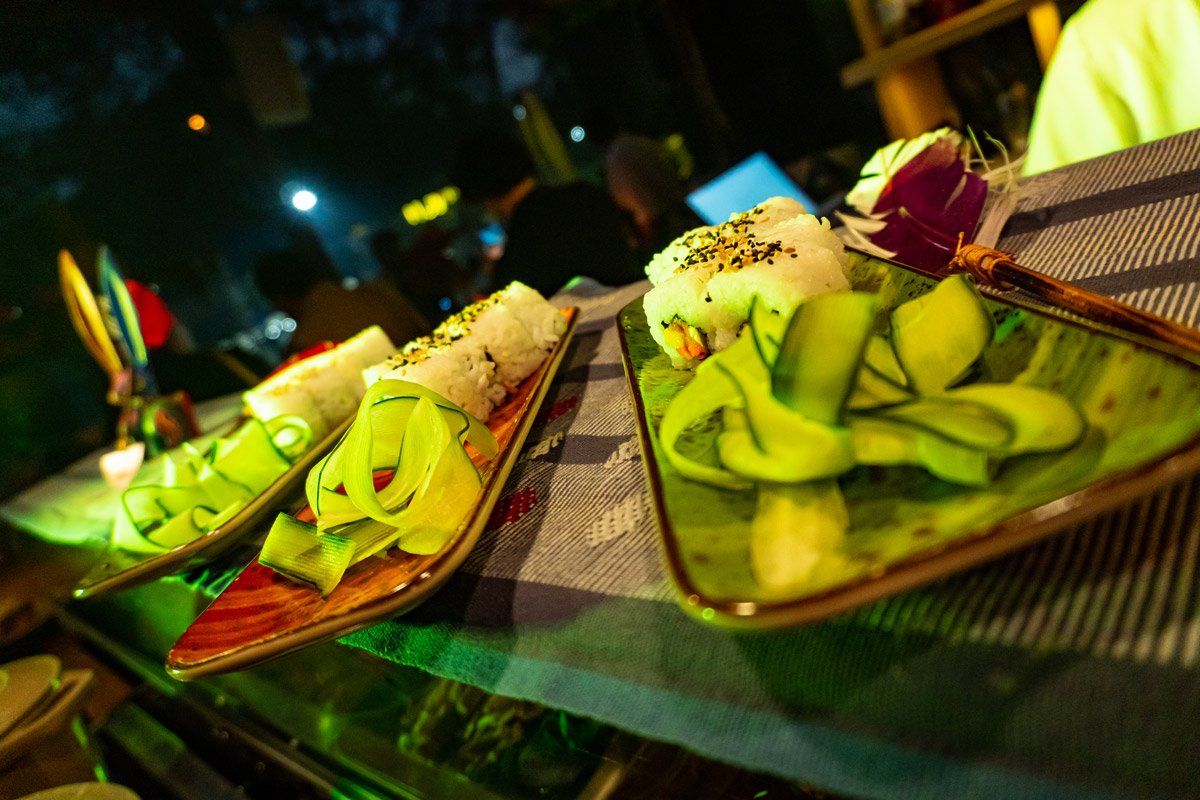 Platos de rollos de sushi y cintas de pepino, colocados sobre una superficie de rayas azules y blancas.