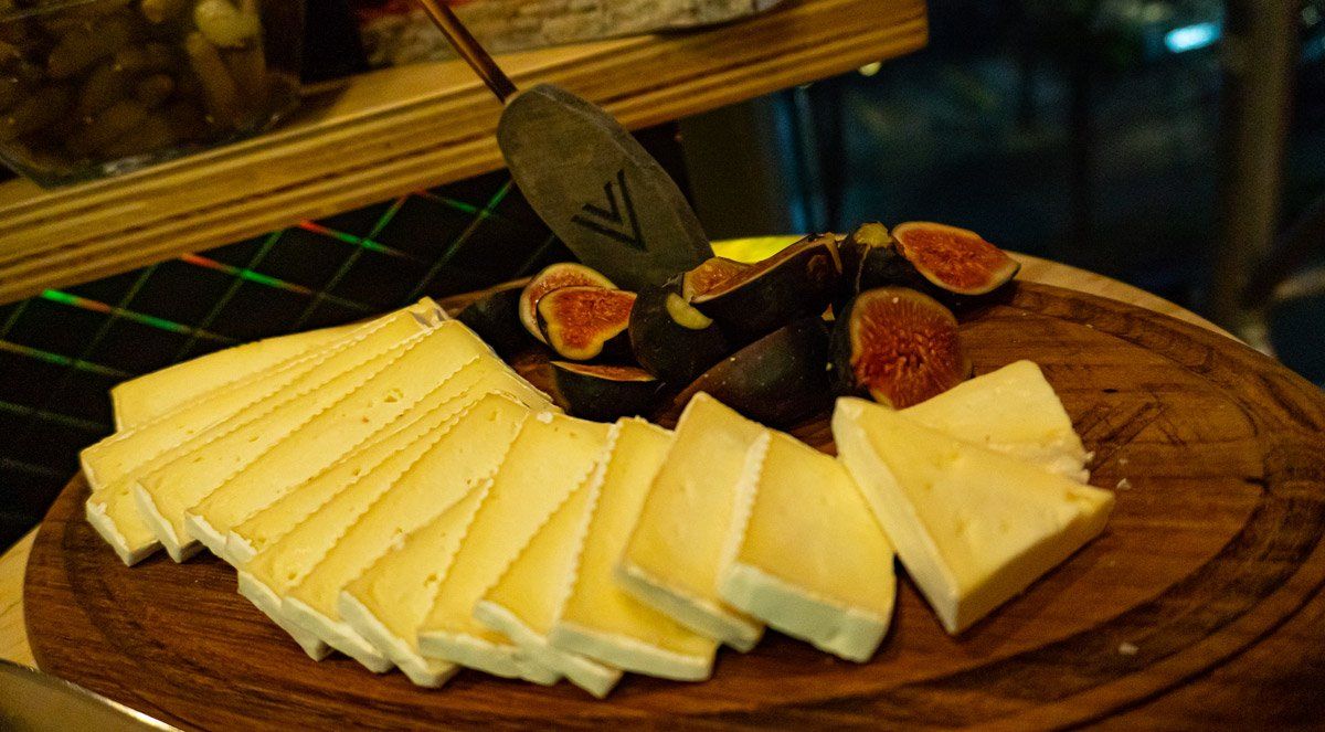 Queso e higos en una bandeja de madera con un cuchillo para queso.