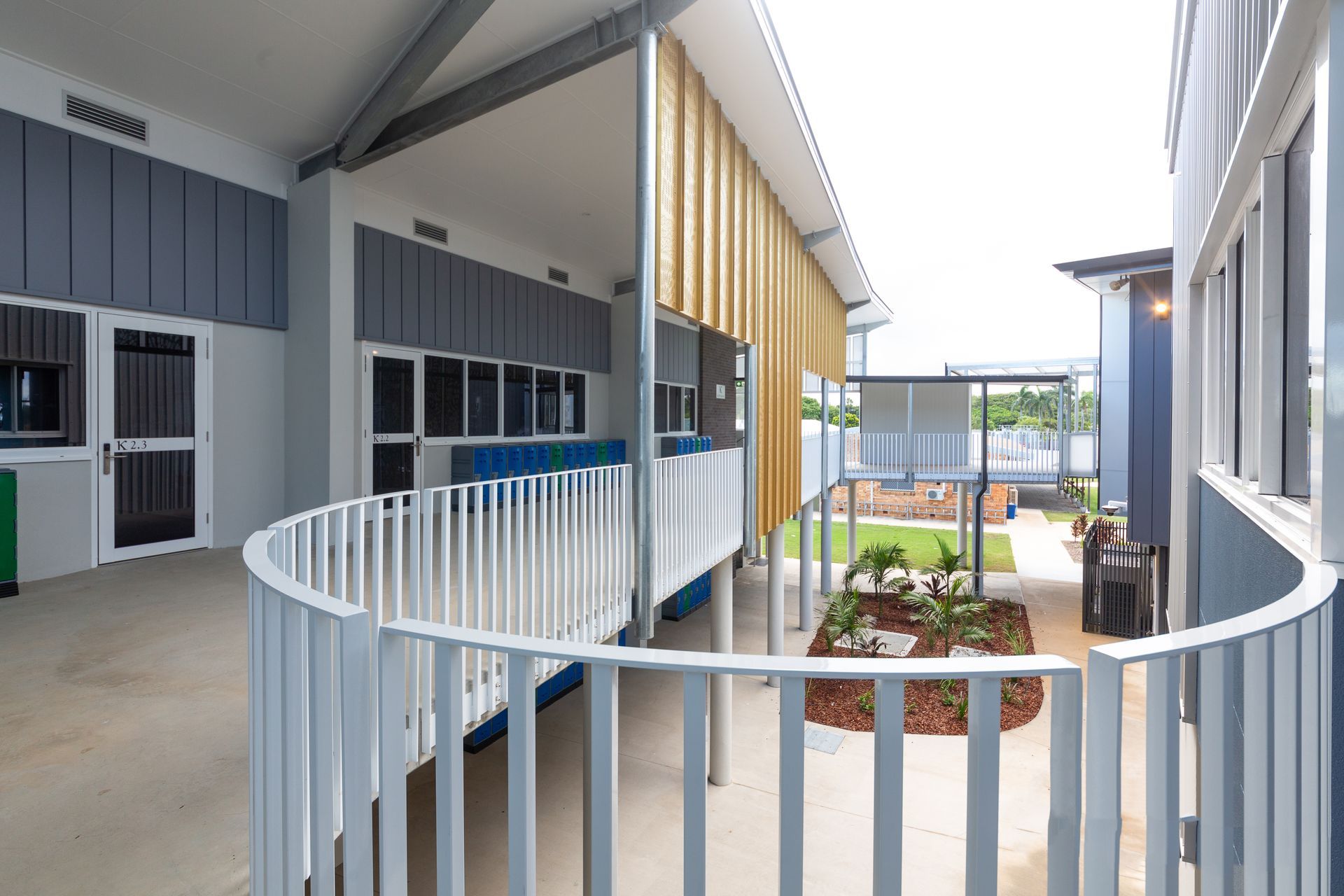 Outdoor School Corridor With Curved White Railing and Flower Bed — BOLD Architecture + Interior Design In Mackay, QLD