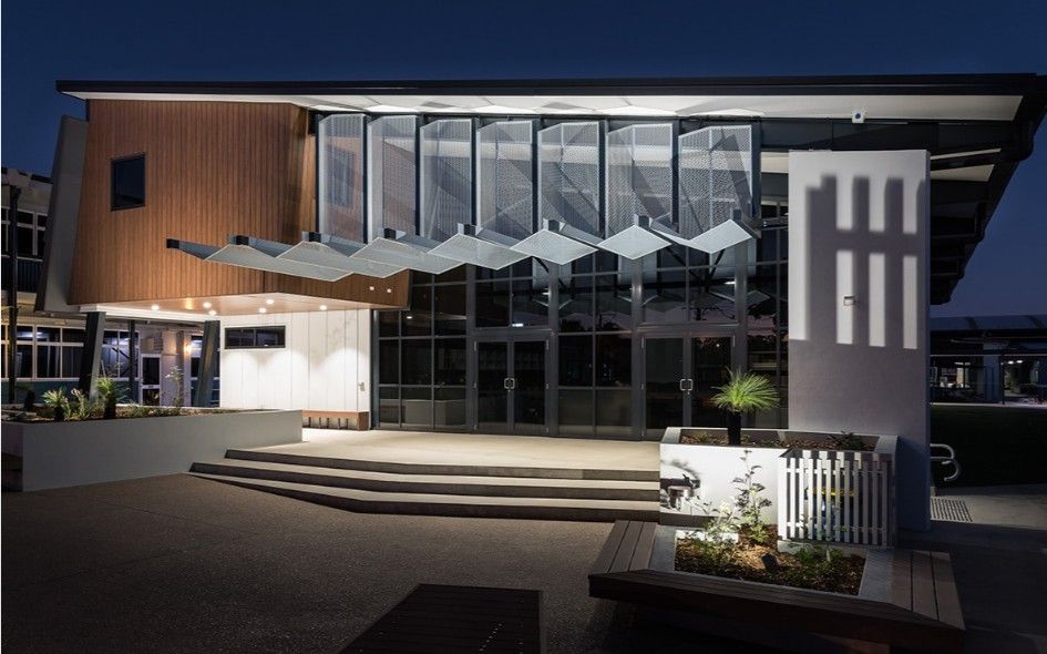 Nighttime Exterior of Modern Building Entrance With Glass Doors, Wood Paneling, and Decorative Canopy — BOLD Architecture + Interior Design In Mackay, QLD