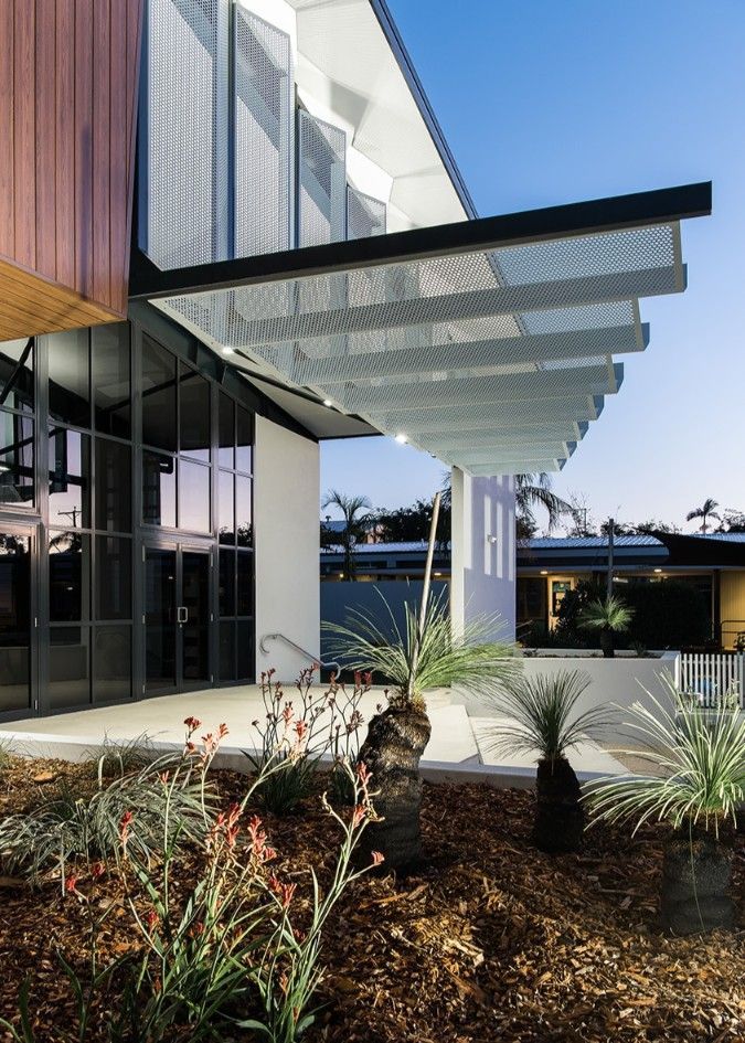 Modern Building Exterior With a Metal Awning, Glass Doors, and Landscaping at Dusk — BOLD Architecture + Interior Design In Mackay, QLD