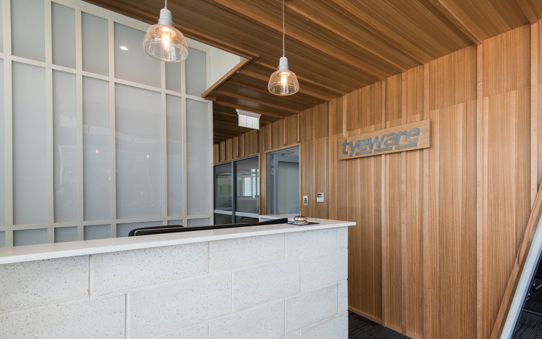 Reception Desk With Stone Counter, Wood Paneling, and Glass Pendant Lights — BOLD Architecture + Interior Design In Mackay, QLD