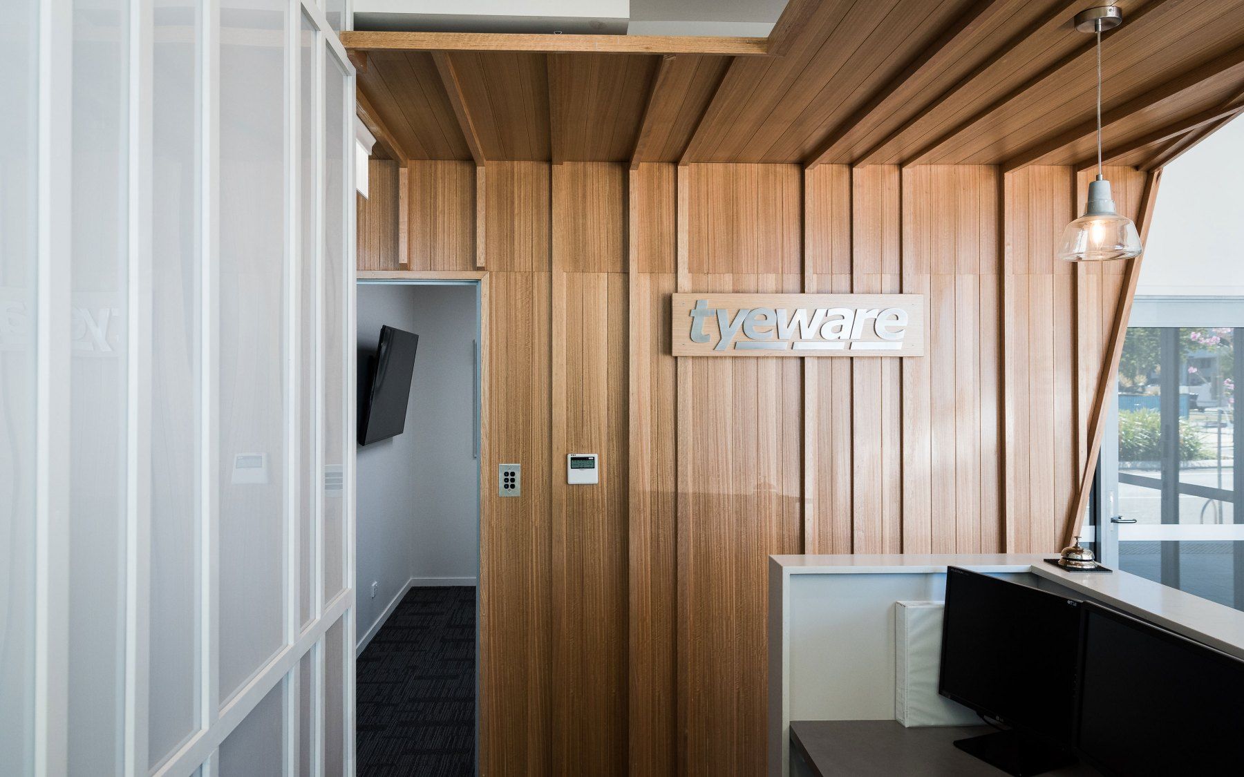Reception Area With Wooden Paneling, Sign, and a Desk With Computer Monitors — BOLD Architecture + Interior Design In Mackay, QLD