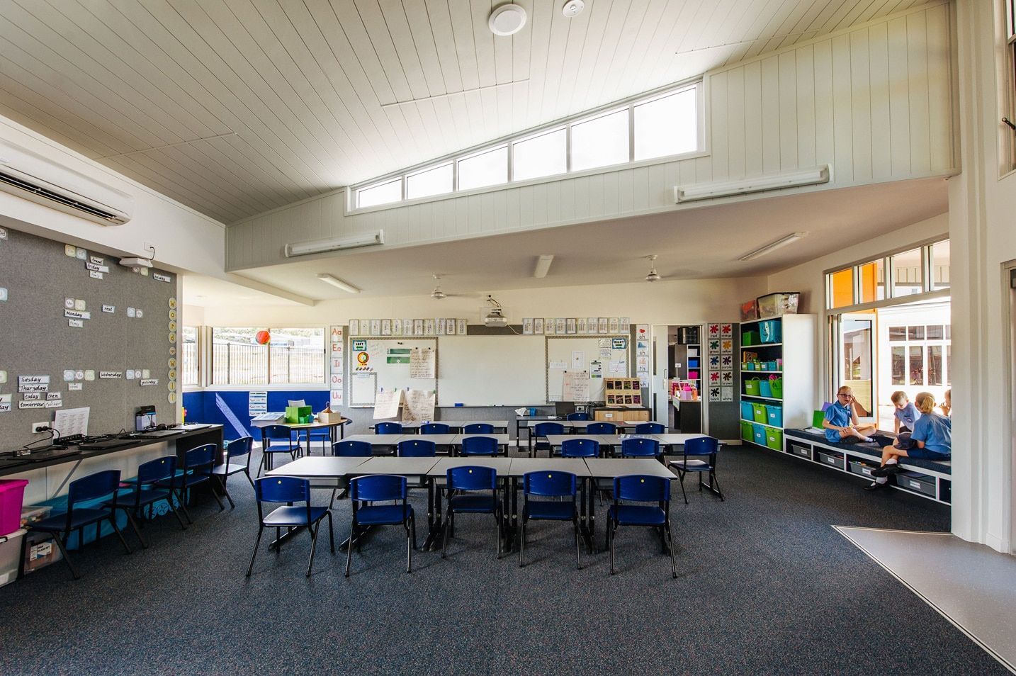Classroom With Desks, Whiteboard, and Children. Blue Chairs, Gray Carpet, and Lots of Natural Light — BOLD Architecture + Interior Design In Mackay, QLD