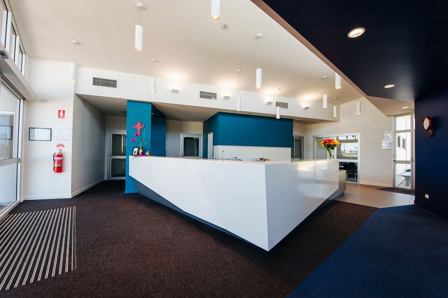 Modern White Reception Desk in a Blue and Gray Lobby; Entrance on the Left — BOLD Architecture + Interior Design In Mackay, QLD