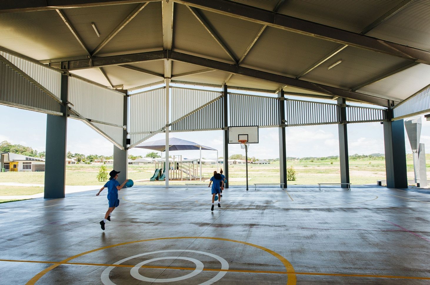 Two Children Playing Basketball on a Court Under a Covered Structure — BOLD Architecture + Interior Design In Mackay, QLD