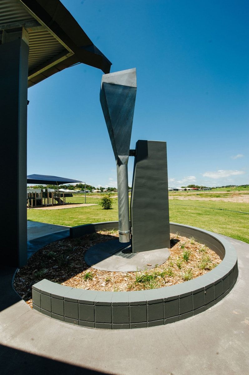 Metal Sculpture With Angled Funnel Shape on Dark Pedestal, Near Building and Landscaped Area — BOLD Architecture + Interior Design In Mackay, QLD