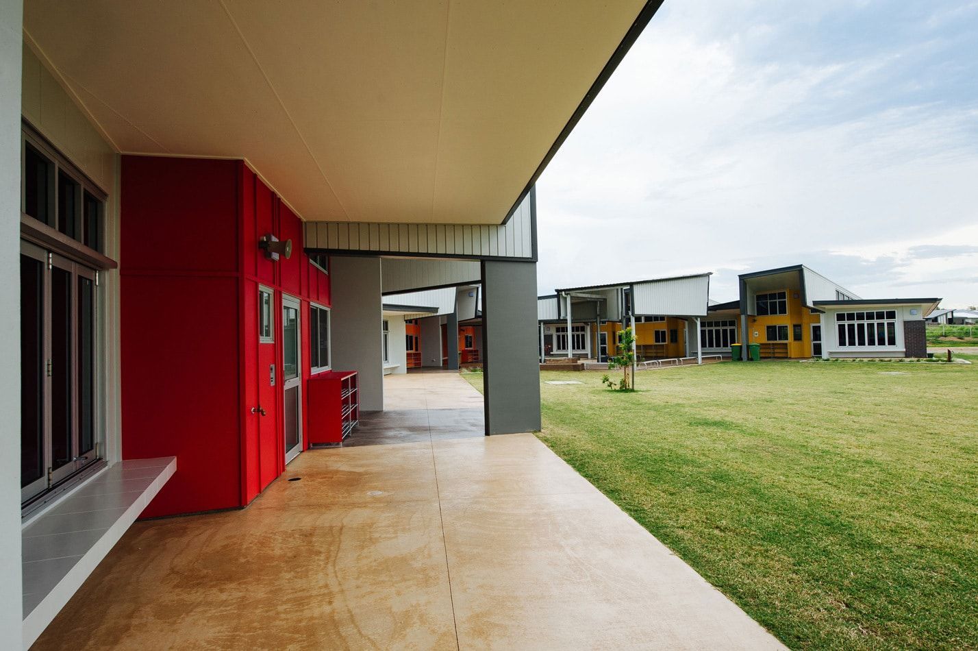 Exterior View of Modern Buildings With a Red Accent, Grassy Area — BOLD Architecture + Interior Design In Mackay, QLD