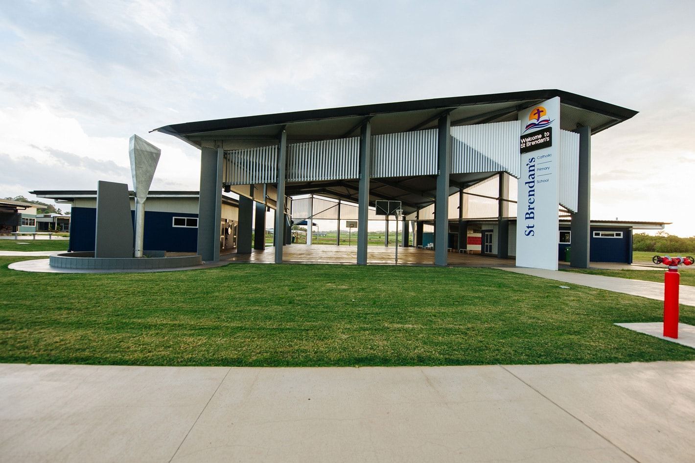 Modern Building With Open Air Design, St. Brendan's Sign, Green Grass, Blue Accents, and White and Grey Features — BOLD Architecture + Interior Design In Mackay, QLD
