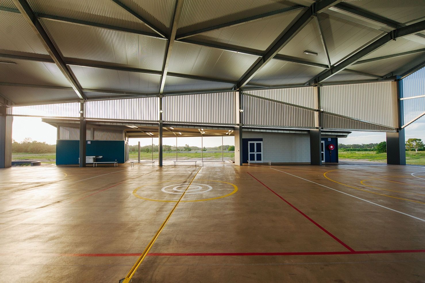 An Open-air Gymnasium With a Concrete Floor, Marked With Lines, and a Geometric Metal Roof — BOLD Architecture + Interior Design In Mackay, QLD